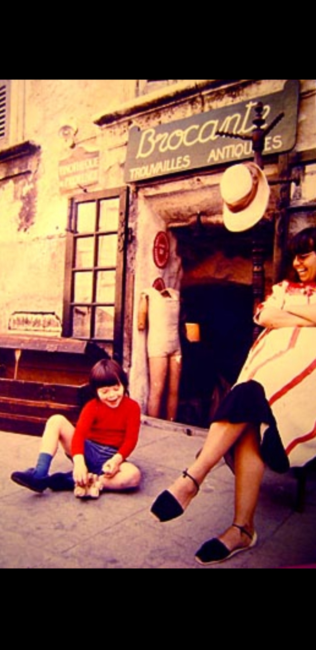 Vintage child with wooden toy outside storefront